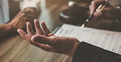 Closeup view of two people's hands while they are working at a shared desk.